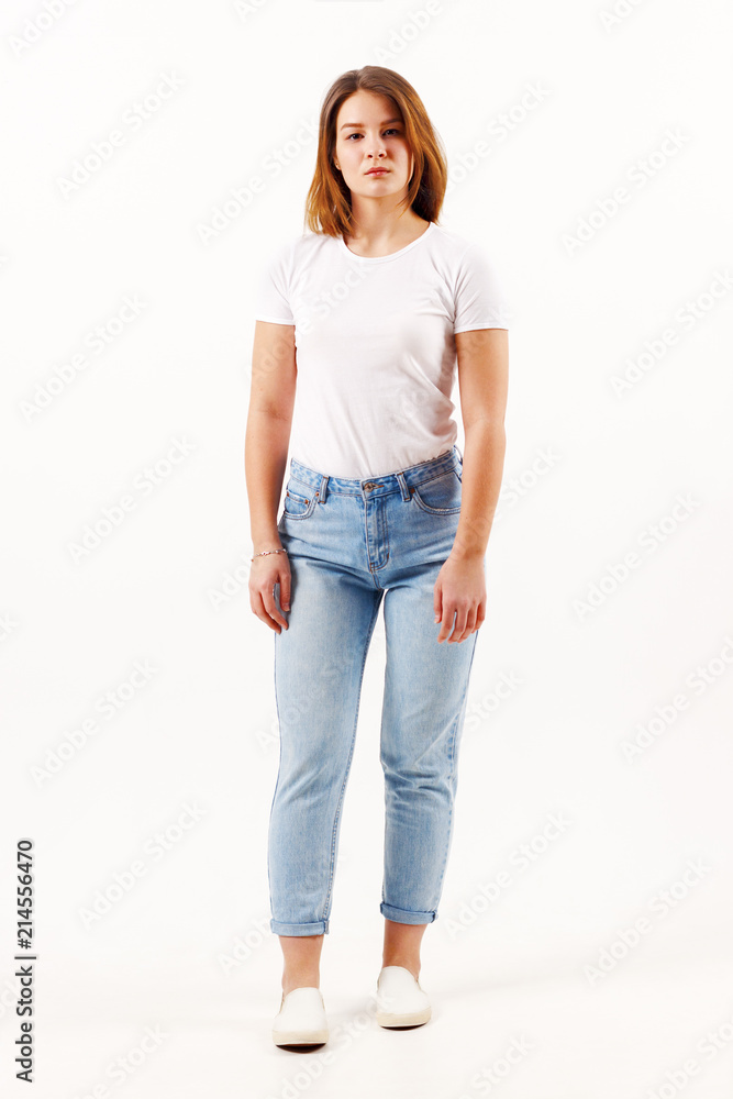 Beautiful girl teenager in white t-shirt and jeans poses in white studio Beautiful girl teenager in white t-shirt and jeans poses in white studio
