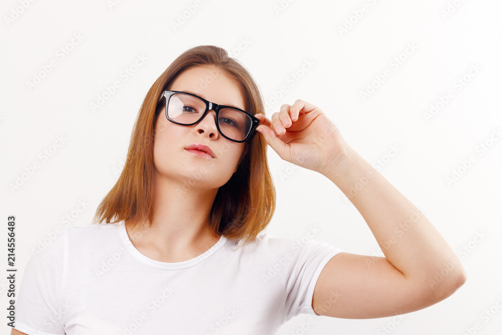Beautiful happy girl teenager in glasses poses in white studio