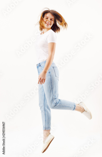 Happy girl teenager in t-shirt and jeans jumps in white studio, full body