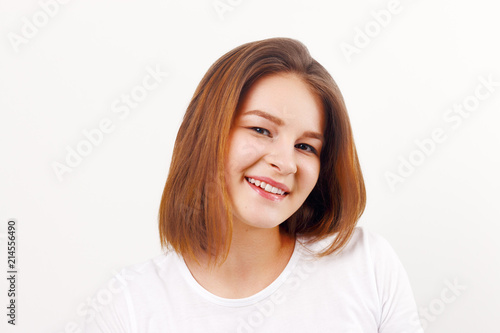 Beautiful happy girl teenager in white t-shirt smiles in white studio