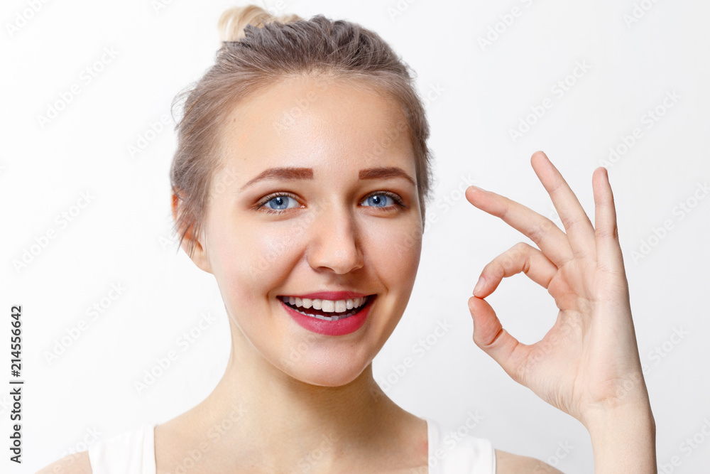 Pretty young girl with make-up shows Ok gesture in studio, close up portrait Pretty young girl with make-up shows Ok gesture in studio, close up portrait
