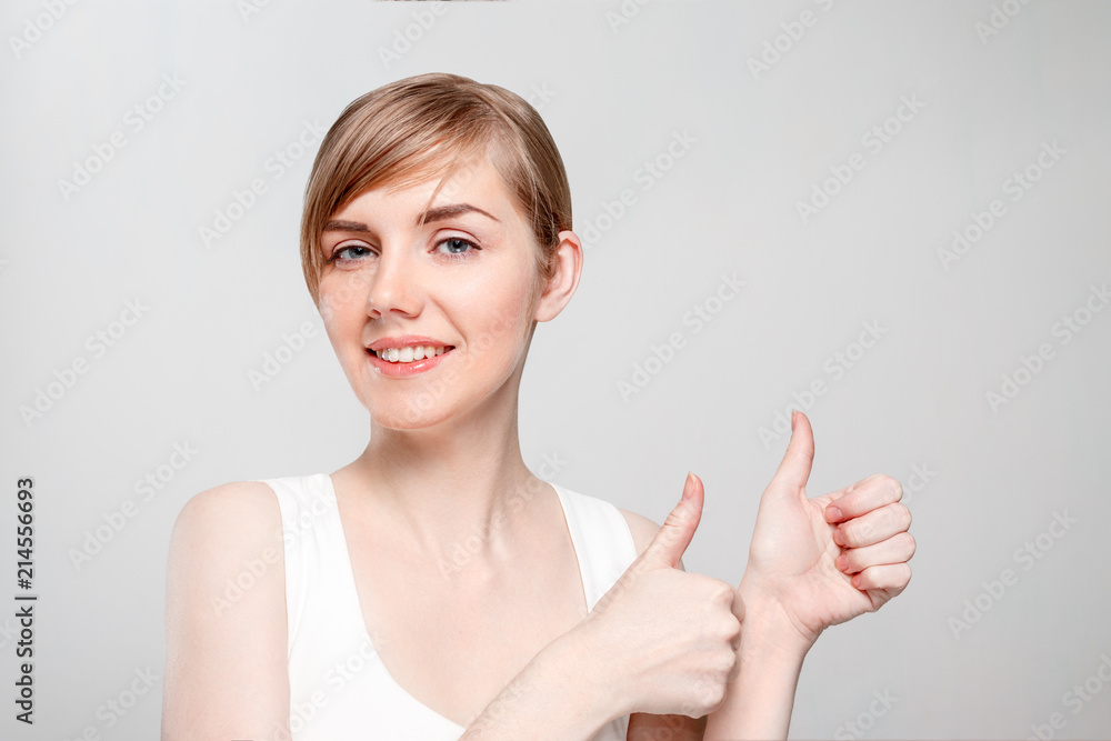 Beautiful young woman with make-up thumbs up and smiles in studio Beautiful young woman with make-up thumbs up and smiles in studio