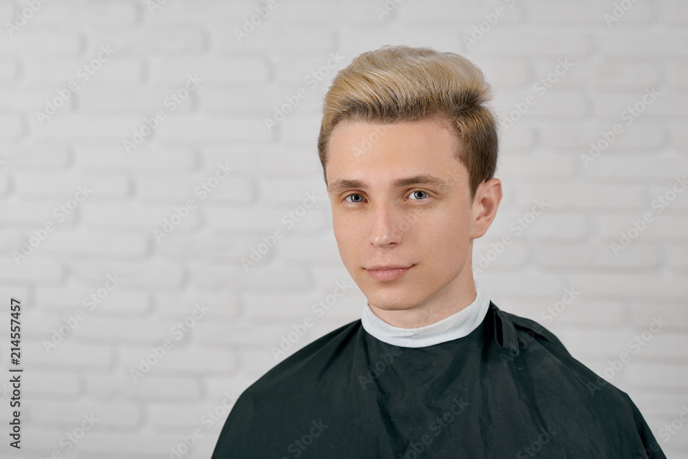 Young male model with blonde hair waiting for new hairstyle sitting on  white background. Looking at