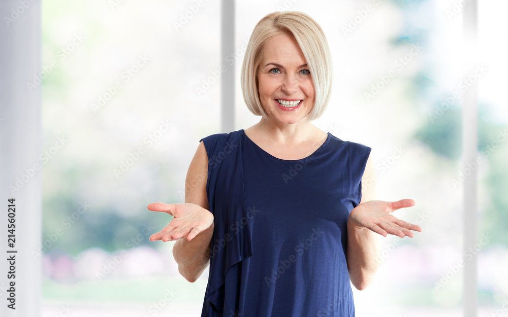 Εκτύπωση καμβά Attractive middle aged woman with a beautiful smile near the window