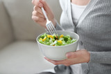 Young woman eating fresh salad at home. Healthy food concept