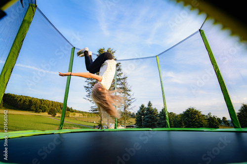 Kind auf Trampolin - Salto rückwärts dynamisch photo