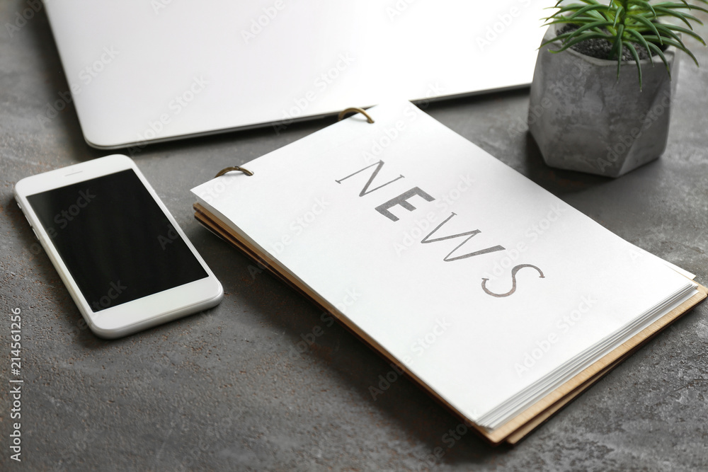 Notebook with word NEWS and phone on table Notebook with word NEWS and phone on table
