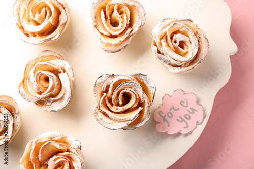Board with tasty apple roses from puff pastry on table