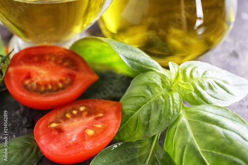 Fresh basil leaves and tomatoes on table, closeup