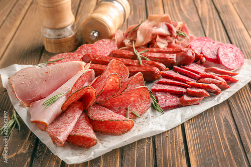 Fotografie Variety of delicious deli meats on wooden table