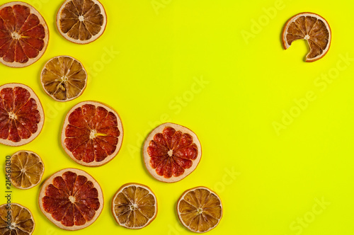 Scattered dried slices grapefruit and lemon on yellow background. Top view with copy space photo