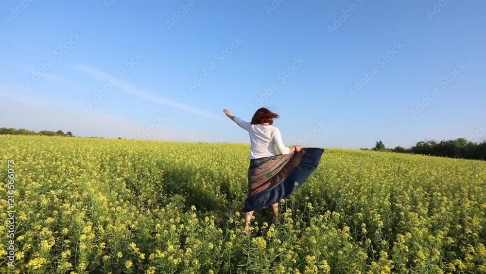 A young woman runs along a yellow flowering meadow. Rejoices and bounces A young woman runs along a yellow flowering meadow. Rejoices and bounces