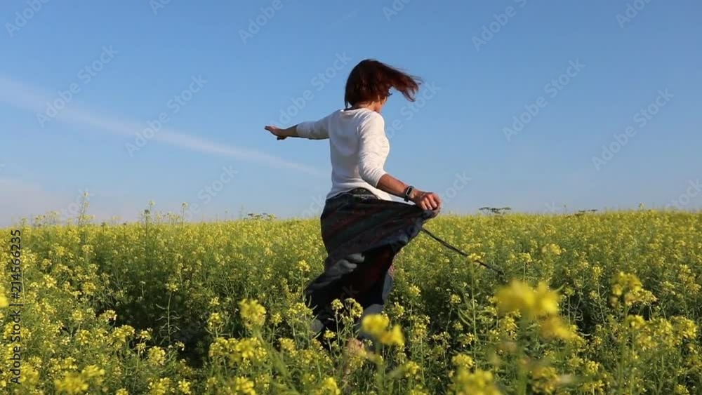 A young woman runs along a yellow flowering meadow. Rejoices and bounces A young woman runs along a yellow flowering meadow. Rejoices and bounces