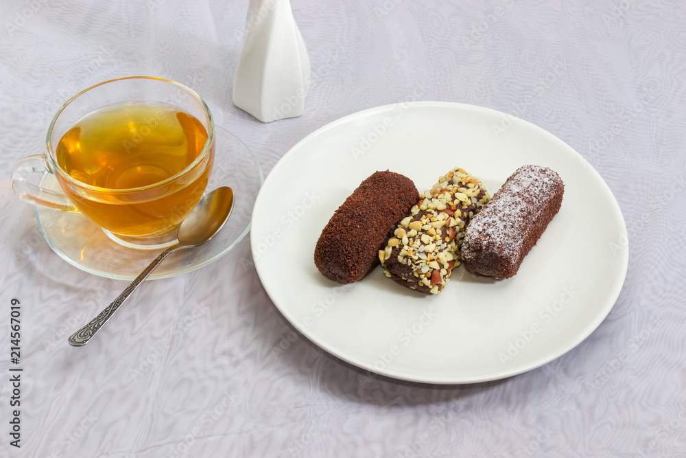 Three chocolate pastries with different sprinklings and cup of tea Three chocolate pastries with different sprinklings and cup of tea