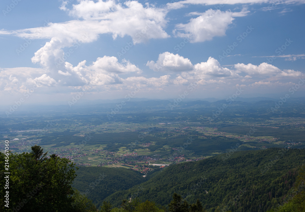 Fototapeta premium View from Medvednica, Sljeme mountain in Zagreb, Croatia. Landscape photo with blue sky, white clouds and green trees