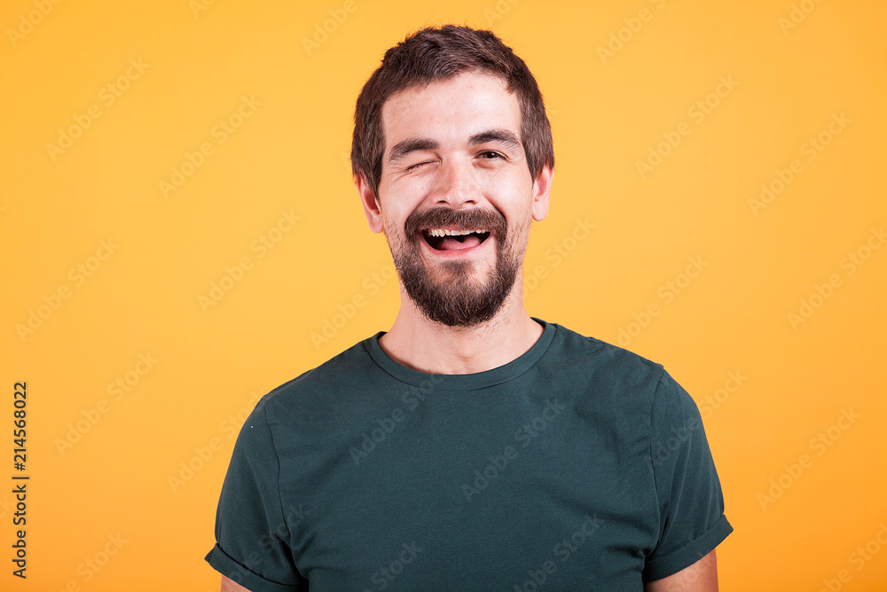 Fototapeta premium Happy positive man looking at the camera and winking isolated on yellow background