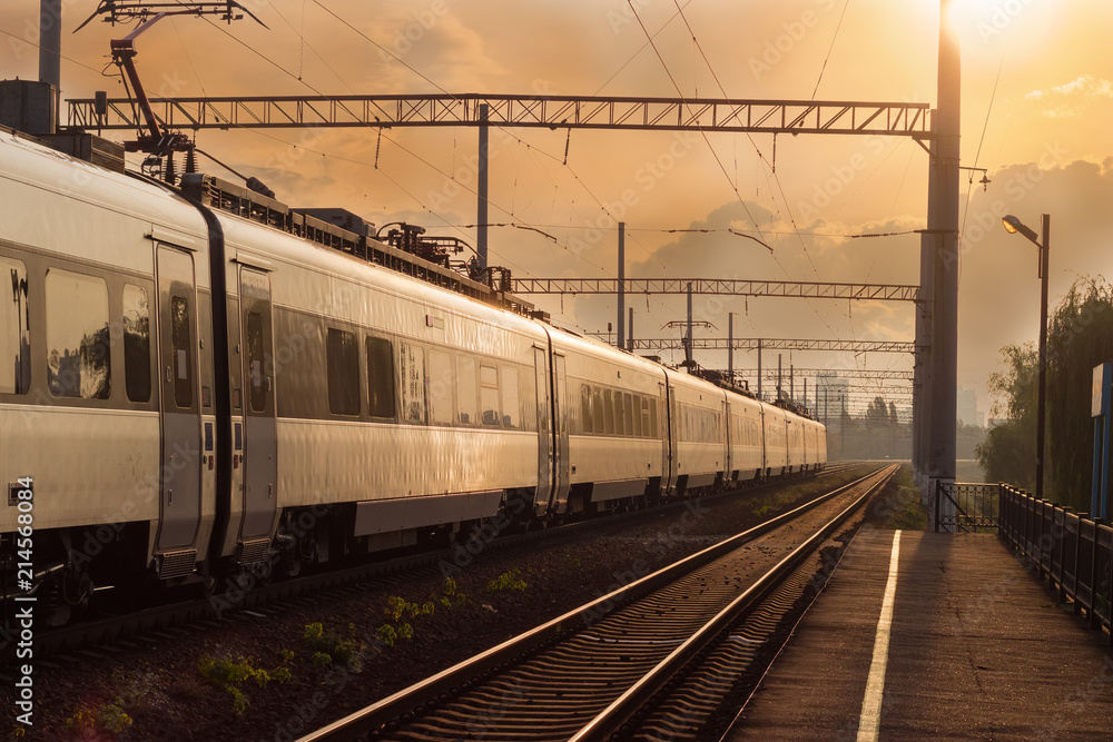Fototapeta premium Passenger inter-city train in city on the sunset background