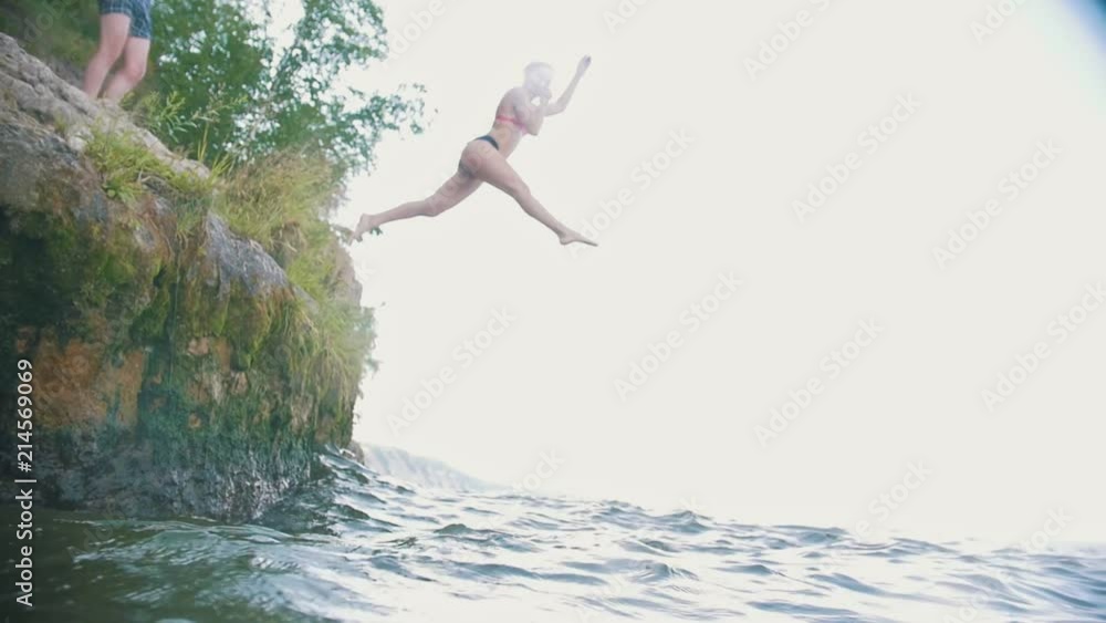 Girl dives into the water from a rock in nature, slow motion Girl dives into the water from a rock in nature, slow motion