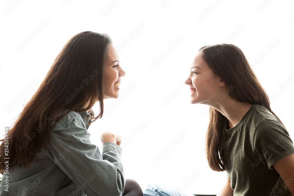 Two sisters playing with each other and having a great time together over white background Two sisters playing with each other and having a great time together over white background