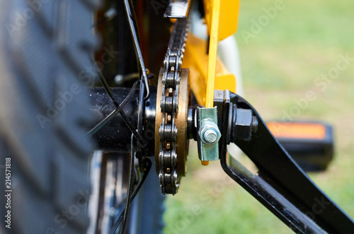 Kids yellow bicycle in park, close up parts, rear tire with brakes and chain