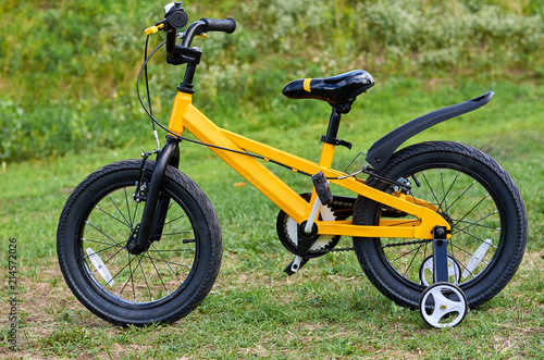 Kids yellow bicycle in park, close up parts