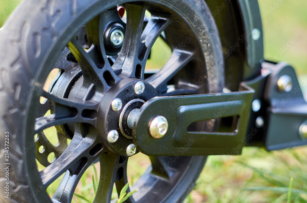 Black folding kick scooter, close up parts, rear wheel Black folding kick scooter, close up parts, rear wheel