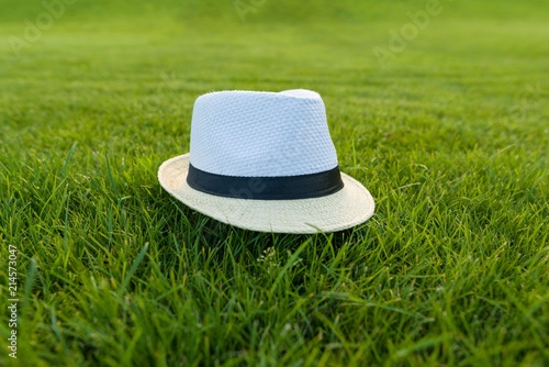Straw hat on green grass lawn texture.