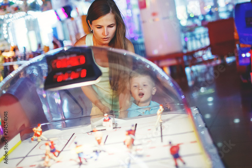 Family mother and little boy playing table hockey arcade in game machine at an amusement park Fototapet