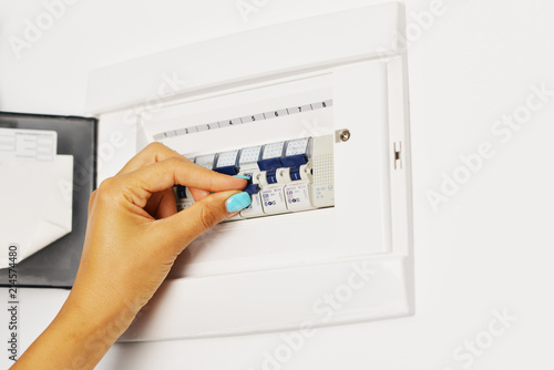 Woman’s hand turning off electrical fuse box
 photo