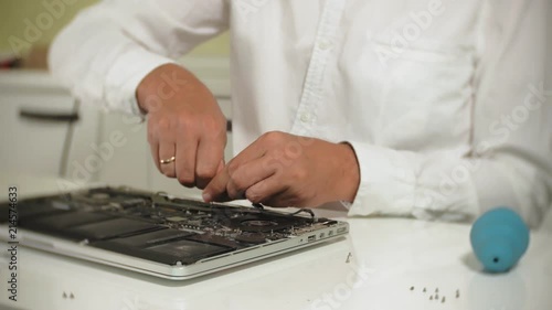 A man is repairing a laptop. The concept of computer repair. Close up of man repair laptop motherboard with a screwdriver. Maintenance of the hardware of the motherboard. Disc holder, computer repair