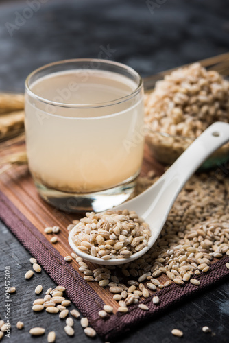Barley water in glass with raw and cooked pearl barley wheat/seeds. selective focus
