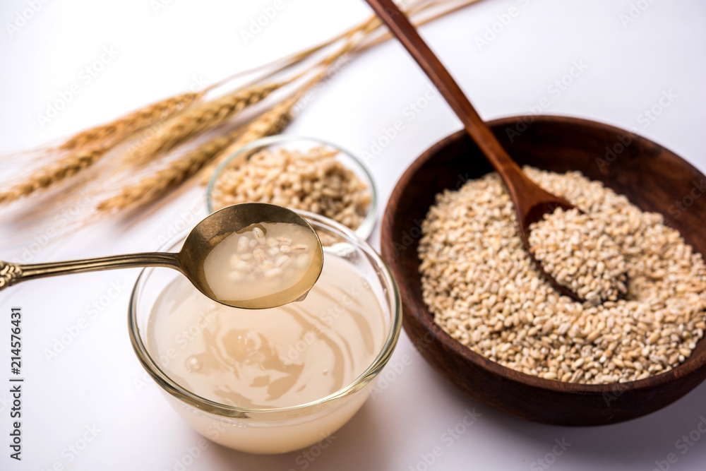 Barley water in glass bowl with spoon and raw and cooked pearl barley wheat/seeds. selective focus Barley water in glass bowl with spoon and raw and cooked pearl barley wheat/seeds. selective focus