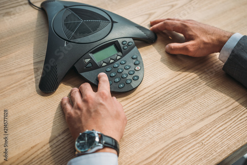 Φωτογραφία cropped shot of businessman with stylish wristwatch using speakerphone at workpl