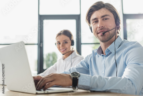 male and female call center managers working together at modern office and looking at camera photo