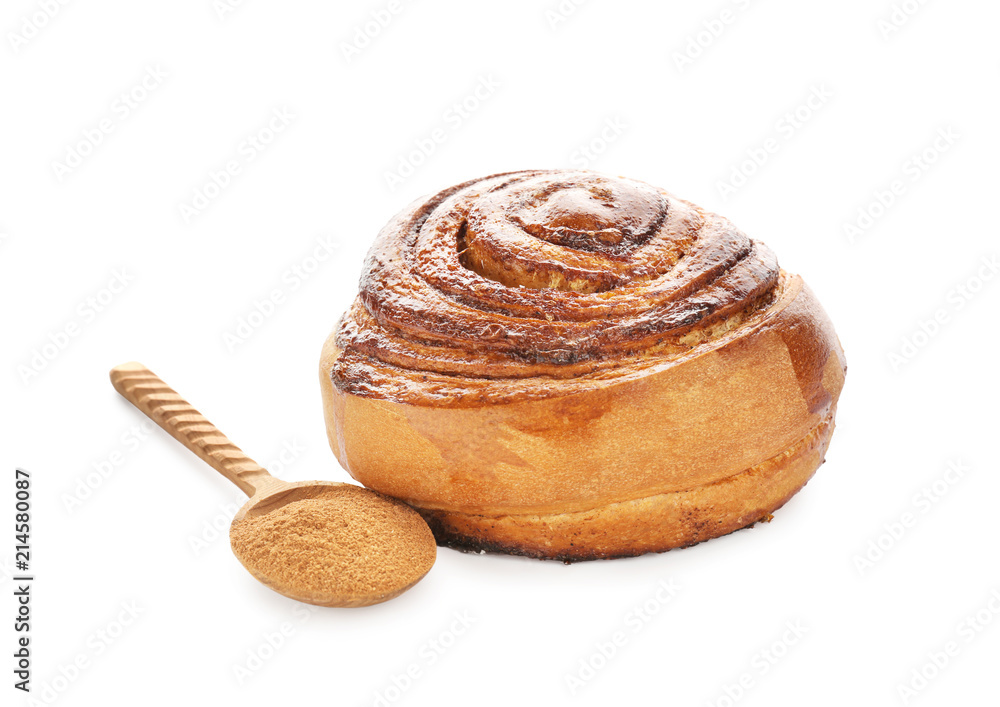 Delicious bun and spoon with cinnamon powder on white background Delicious bun and spoon with cinnamon powder on white background