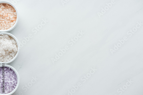 top view of colorful sea salt in bowls on white background