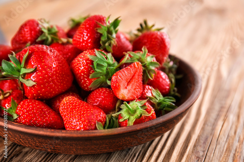 Plate with ripe red strawberries on wooden table  closeup