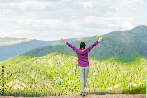 Happy woman raising arms and feeling the freedom in mountains