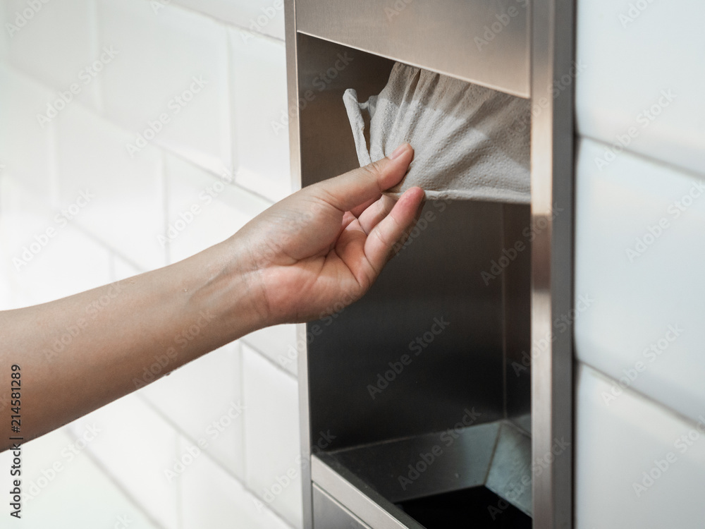 Man hand pulling a tissue paper from tissue box in the restroom.