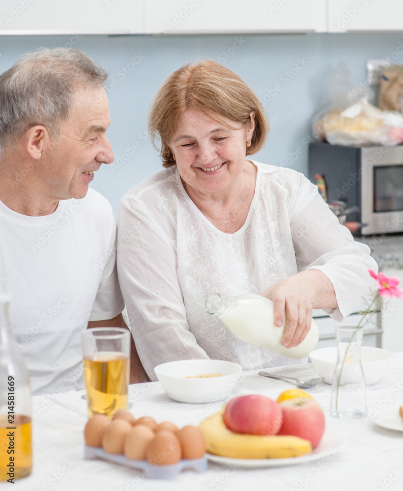 Smiling elderly couple having breakfast in the kitchen of the house Smiling elderly couple having breakfast in the kitchen of the house