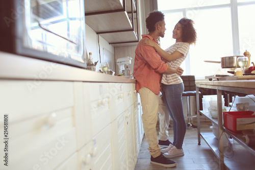 Young African-American couple hugging in kitchen