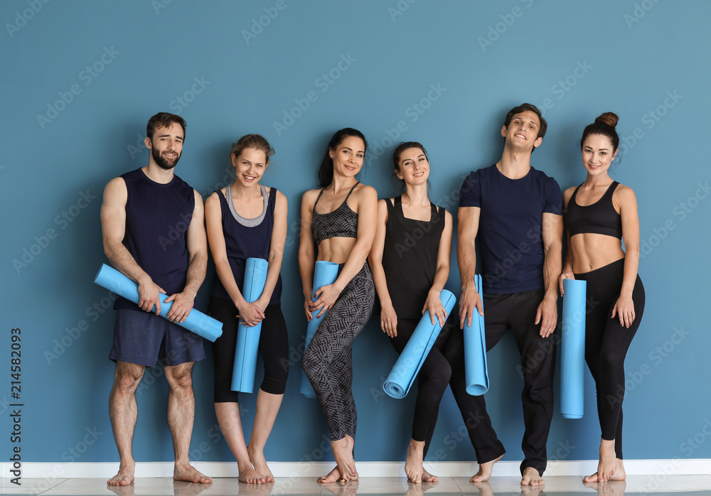 Fototapeta premium Group of people with yoga mats near color wall