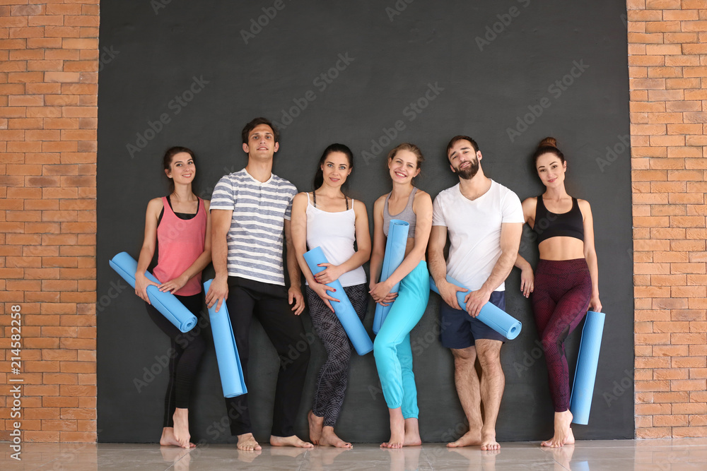 Fototapeta premium Group of people with yoga mats on dark background