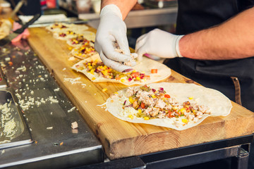 Chef's hands preparing mexican tacos at a street food market, festival, event. Process cooking. Street food concept. Selective focus. copy space.