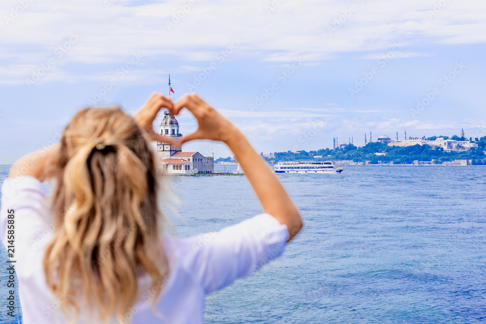 Φωτογραφία Beautiful woman traveler makes heart shape with hands on view of Maidens Tower,a
