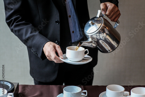 Waiter Pouring Coffee into a white cup.Ready to serve