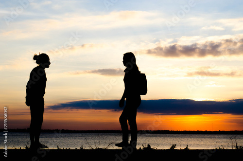 Couple woman silhouette standing very happily talking during sunset and beautiful sky.