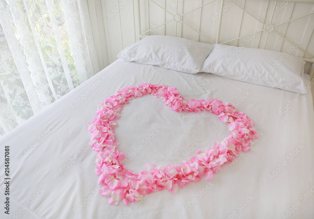 Heart of red petals on a bed. Honeymoon.