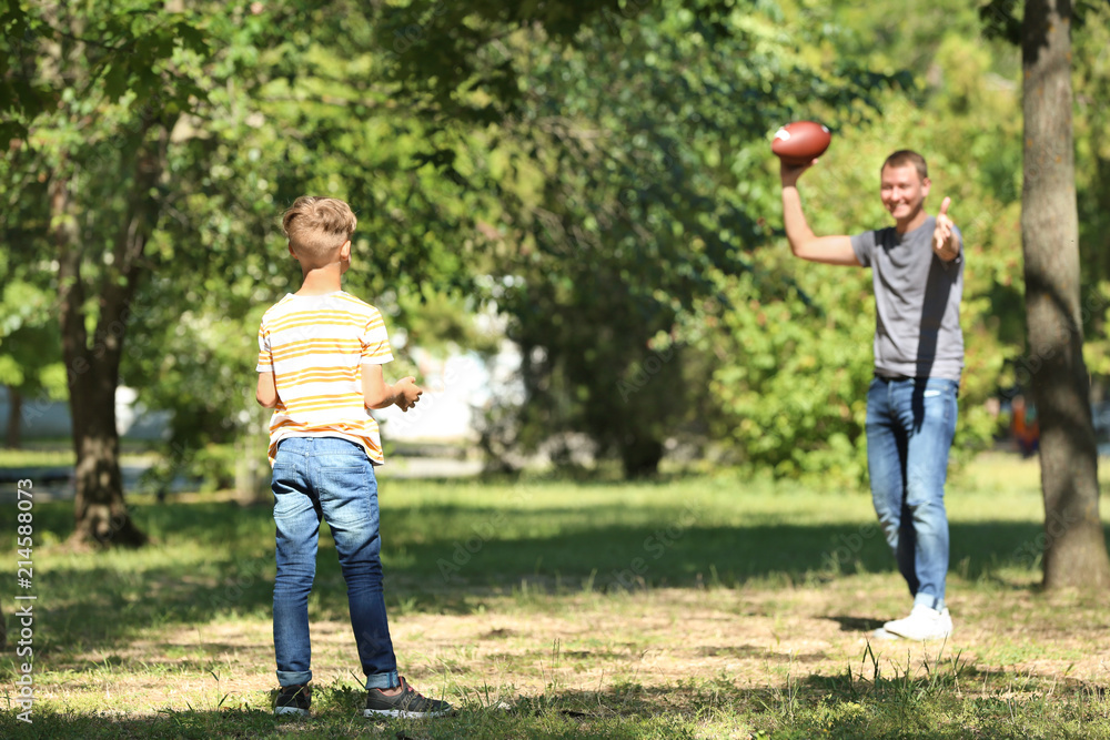 Happy father and son playing rugby in park Happy father and son playing rugby in park