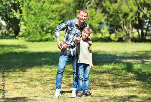Happy father and son with rugby ball in park